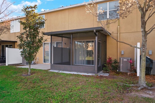 rear view of property featuring central AC unit, a sunroom, and stucco siding