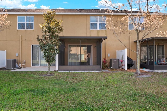 back of property with central air condition unit, stucco siding, a yard, and a sunroom