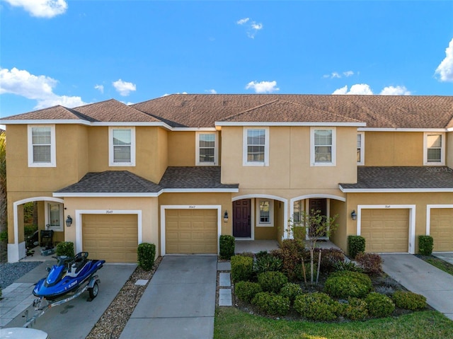 view of property with stucco siding, a garage, concrete driveway, and a shingled roof