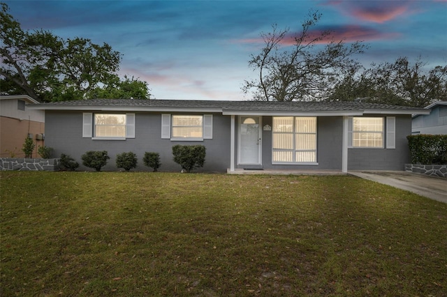 single story home featuring concrete block siding, a front lawn, and a shingled roof