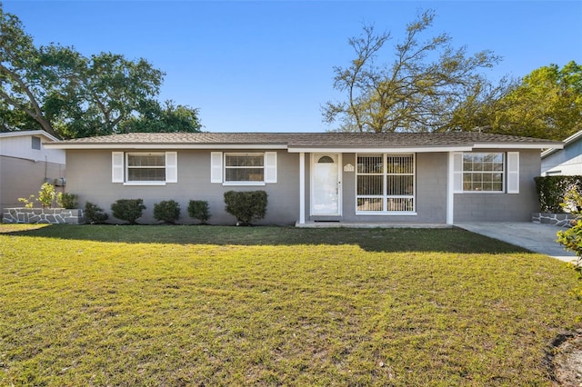 single story home featuring concrete block siding, a front yard, and a shingled roof