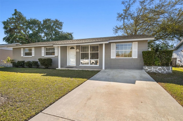 ranch-style house featuring driveway, concrete block siding, a front lawn, and roof with shingles