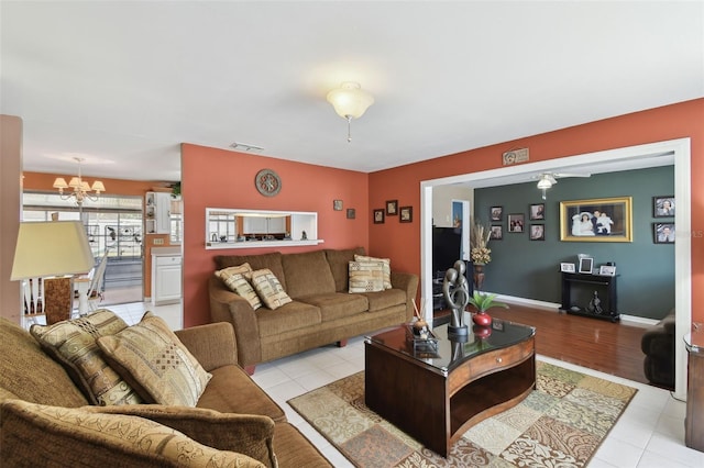 living room featuring light tile patterned floors, baseboards, visible vents, and a chandelier