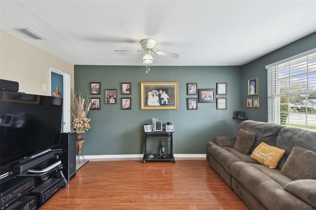 living room featuring baseboards, wood finished floors, visible vents, and ceiling fan