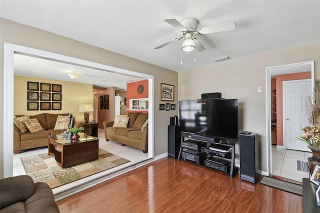 living area with visible vents, wood finished floors, baseboards, and ceiling fan