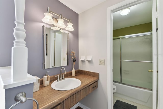 bathroom with vanity, tile patterned floors, toilet, and enclosed tub / shower combo