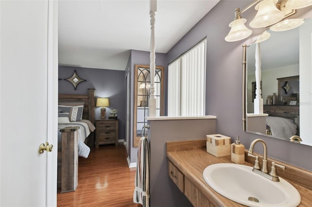 bathroom featuring wood finished floors, ensuite bathroom, baseboards, and a sink