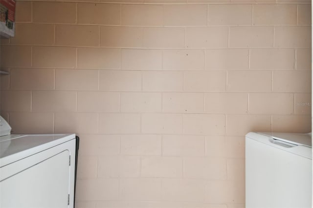 washroom featuring washer and dryer and concrete block wall