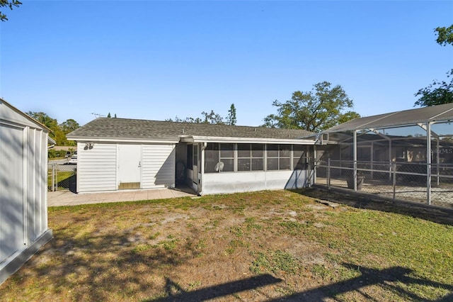 rear view of property with a patio, fence, roof with shingles, a yard, and a lanai