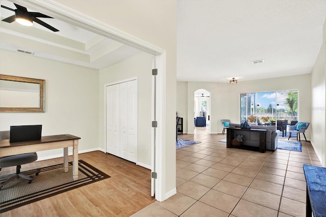home office with visible vents, baseboards, ceiling fan, arched walkways, and light tile patterned floors