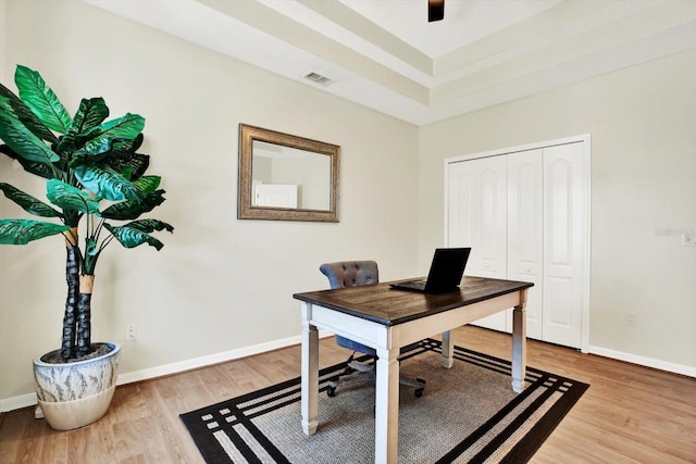 office space with baseboards, visible vents, and wood finished floors