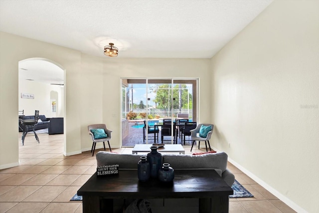 dining room featuring arched walkways, baseboards, and light tile patterned floors