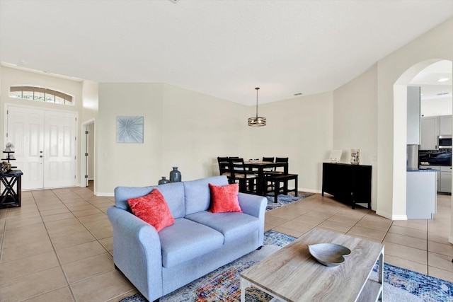 living room with light tile patterned flooring, arched walkways, and baseboards