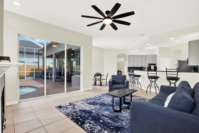 living room with light tile patterned floors, arched walkways, a ceiling fan, and recessed lighting
