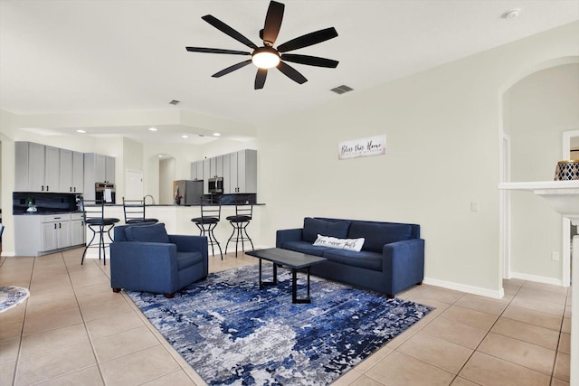 living area featuring arched walkways, a ceiling fan, visible vents, and light tile patterned floors