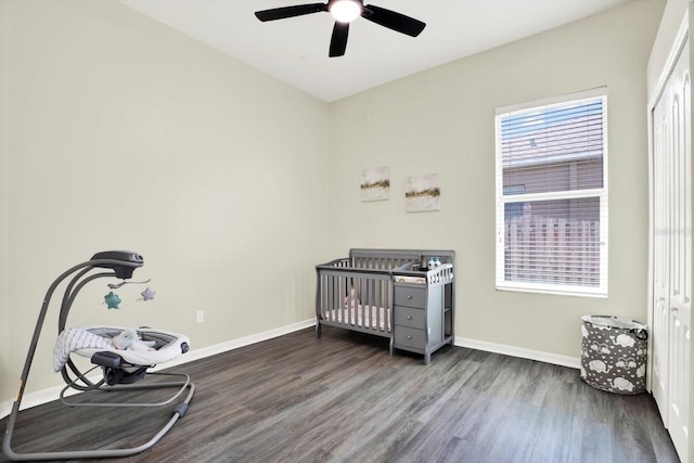 bedroom featuring baseboards, ceiling fan, a crib, and wood finished floors