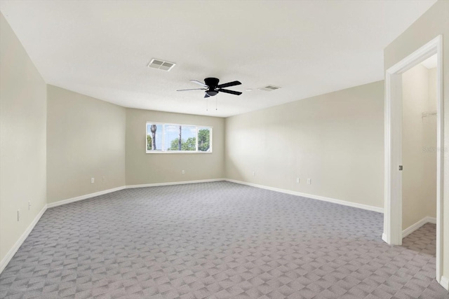 carpeted empty room with baseboards, a ceiling fan, and visible vents