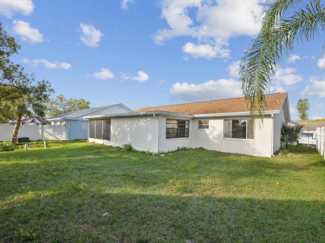 back of house featuring stucco siding, a yard, and fence