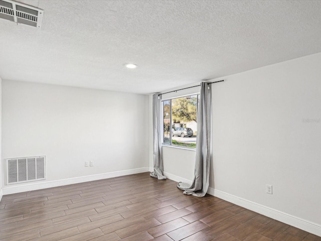 empty room with visible vents, baseboards, and wood finished floors