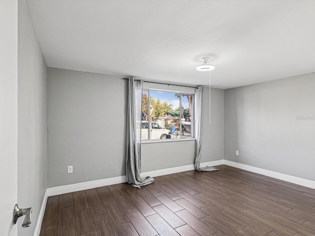 empty room featuring dark wood finished floors and baseboards