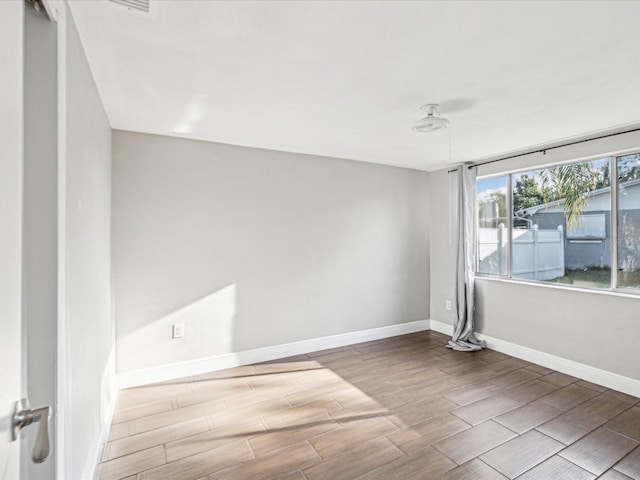 unfurnished room with baseboards and wood tiled floor