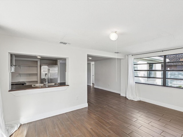 unfurnished living room with a sink, visible vents, baseboards, and wood finished floors