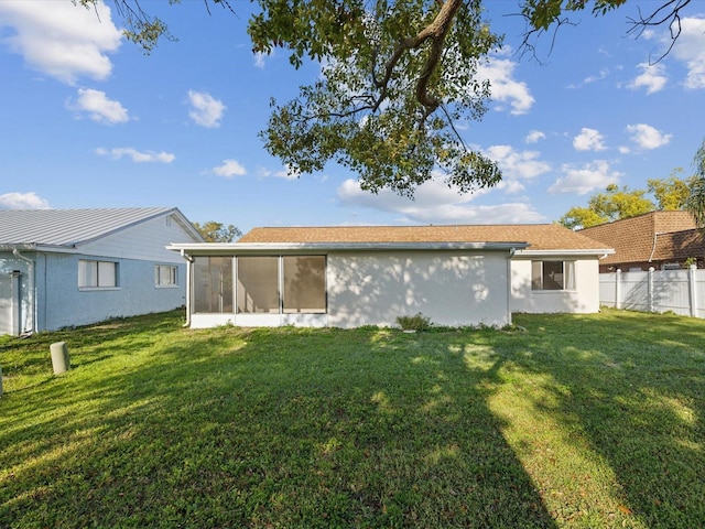 back of property with a yard, fence, a sunroom, and stucco siding