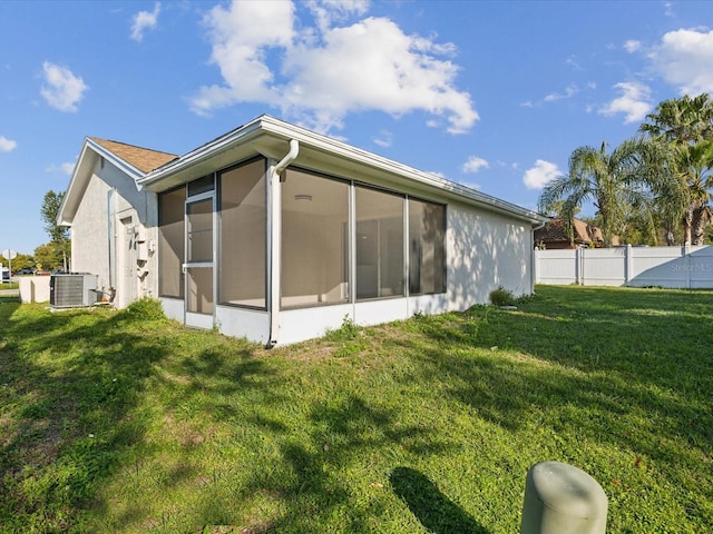 view of side of home with fence, stucco siding, a lawn, cooling unit, and a sunroom