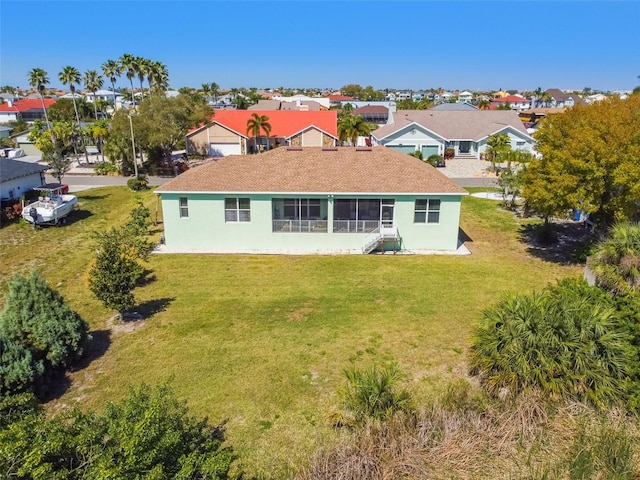 back of property with a lawn, a residential view, and stucco siding