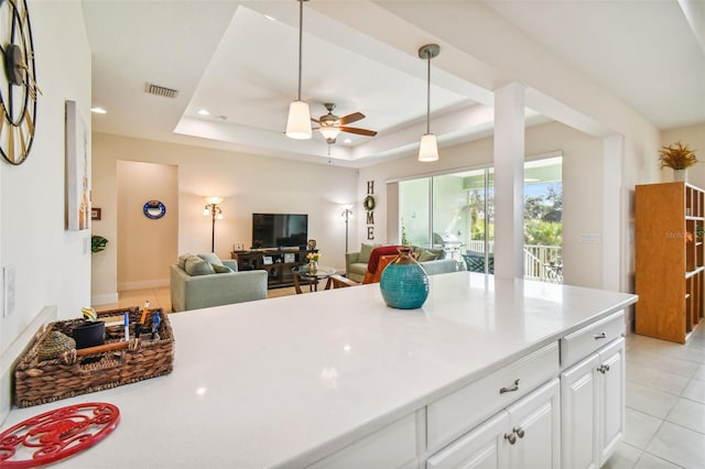 kitchen with visible vents, ceiling fan, pendant lighting, a raised ceiling, and open floor plan