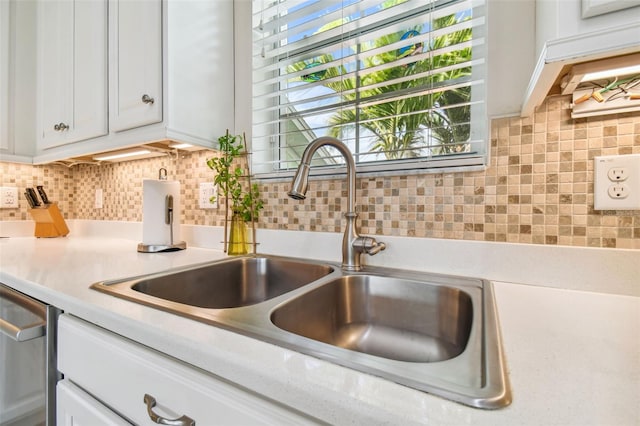 interior space featuring tasteful backsplash, white cabinets, light countertops, and a sink