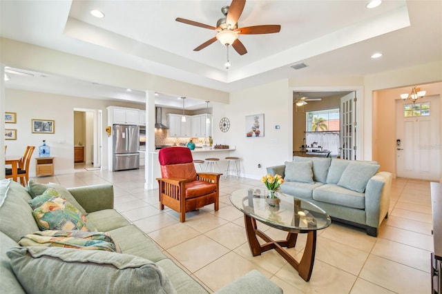 living room featuring visible vents, a raised ceiling, and ceiling fan