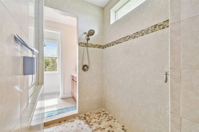 bathroom with tiled shower, a healthy amount of sunlight, and vanity