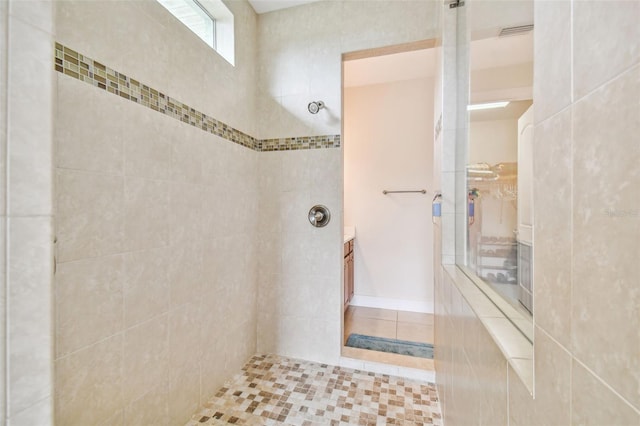 bathroom featuring visible vents, vanity, and a tile shower