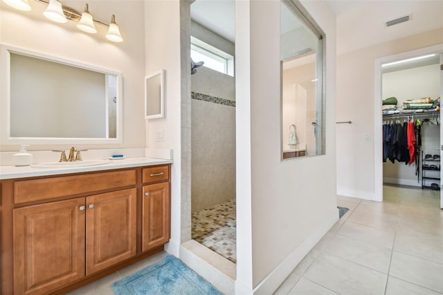 full bathroom featuring tile patterned flooring, vanity, a walk in shower, and visible vents