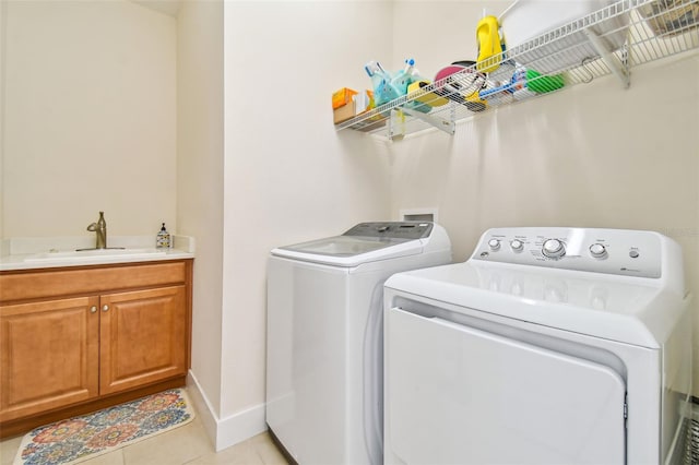 washroom featuring a sink, baseboards, light tile patterned flooring, and washing machine and clothes dryer