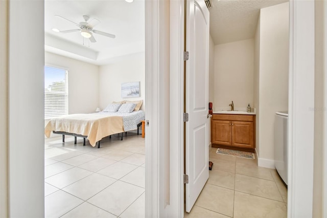 bedroom featuring light tile patterned floors, baseboards, a textured ceiling, and a sink