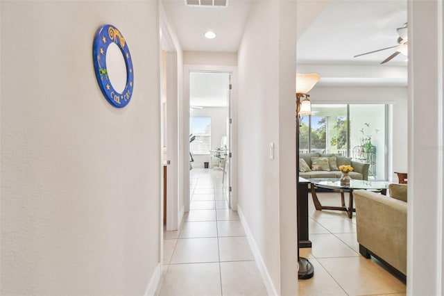 hall featuring light tile patterned floors, visible vents, and baseboards