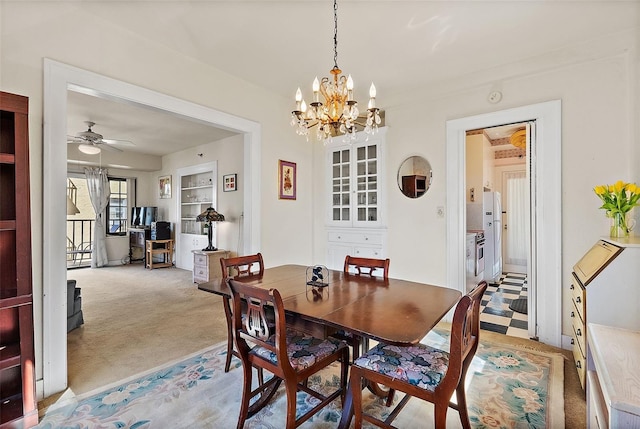 dining space with light colored carpet, built in shelves, and ceiling fan with notable chandelier