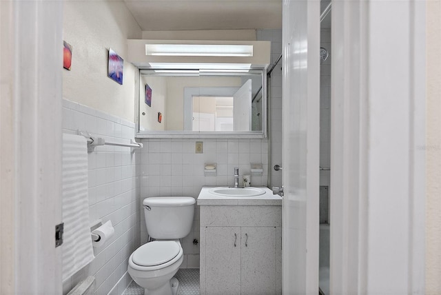 bathroom with wainscoting, vanity, toilet, and tile walls