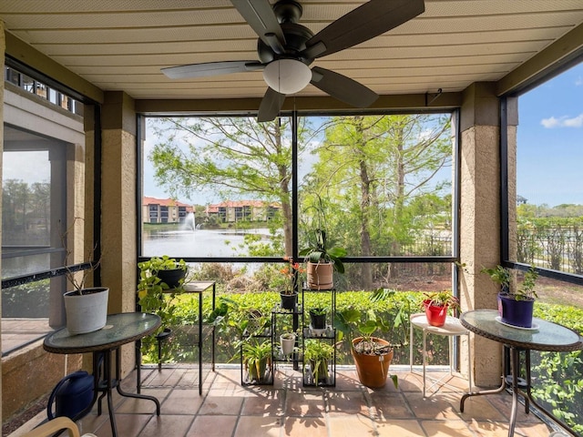 sunroom / solarium with ceiling fan and a water view