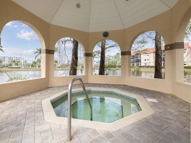 view of pool with a patio area, a community hot tub, and a water view