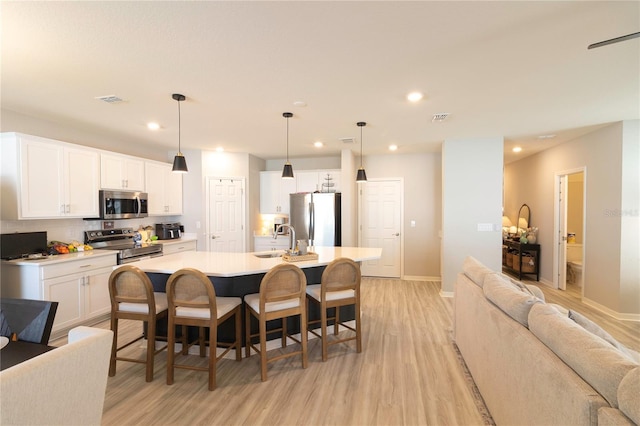 kitchen featuring a sink, stainless steel appliances, visible vents, and open floor plan