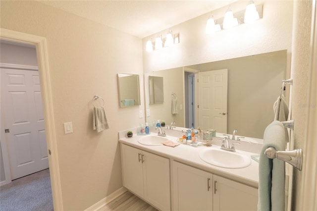 full bathroom with double vanity, baseboards, and a sink