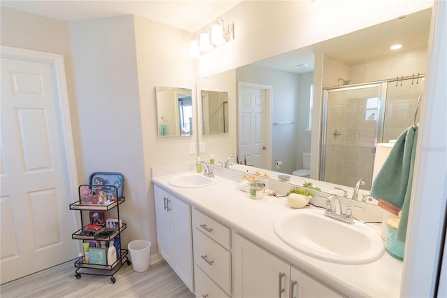 bathroom featuring double vanity, a stall shower, toilet, and a sink