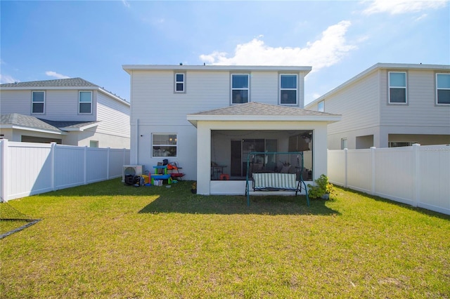 rear view of house with a lawn, a fenced backyard, and a sunroom