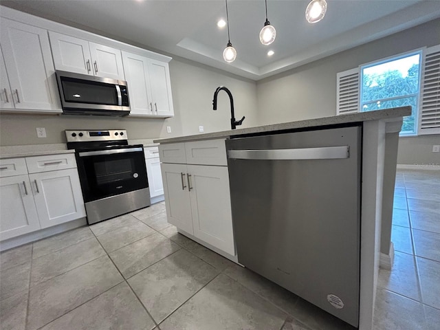 kitchen featuring a tray ceiling, stainless steel appliances, light countertops, white cabinets, and decorative light fixtures