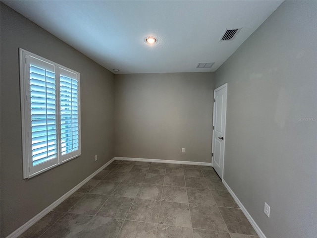 spare room with tile patterned flooring, visible vents, and baseboards