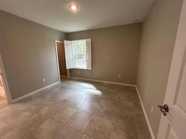 spare room with light tile patterned floors and baseboards