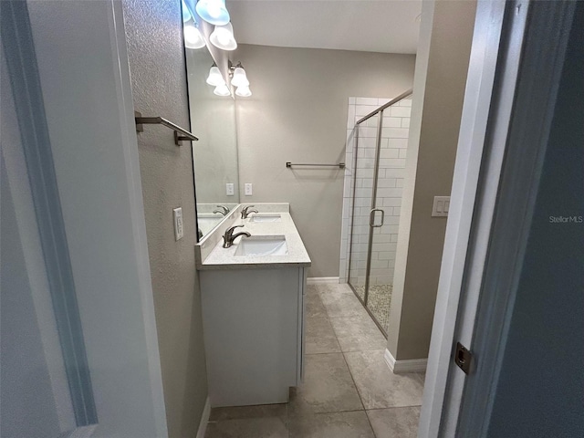 full bathroom with double vanity, a stall shower, baseboards, and a sink